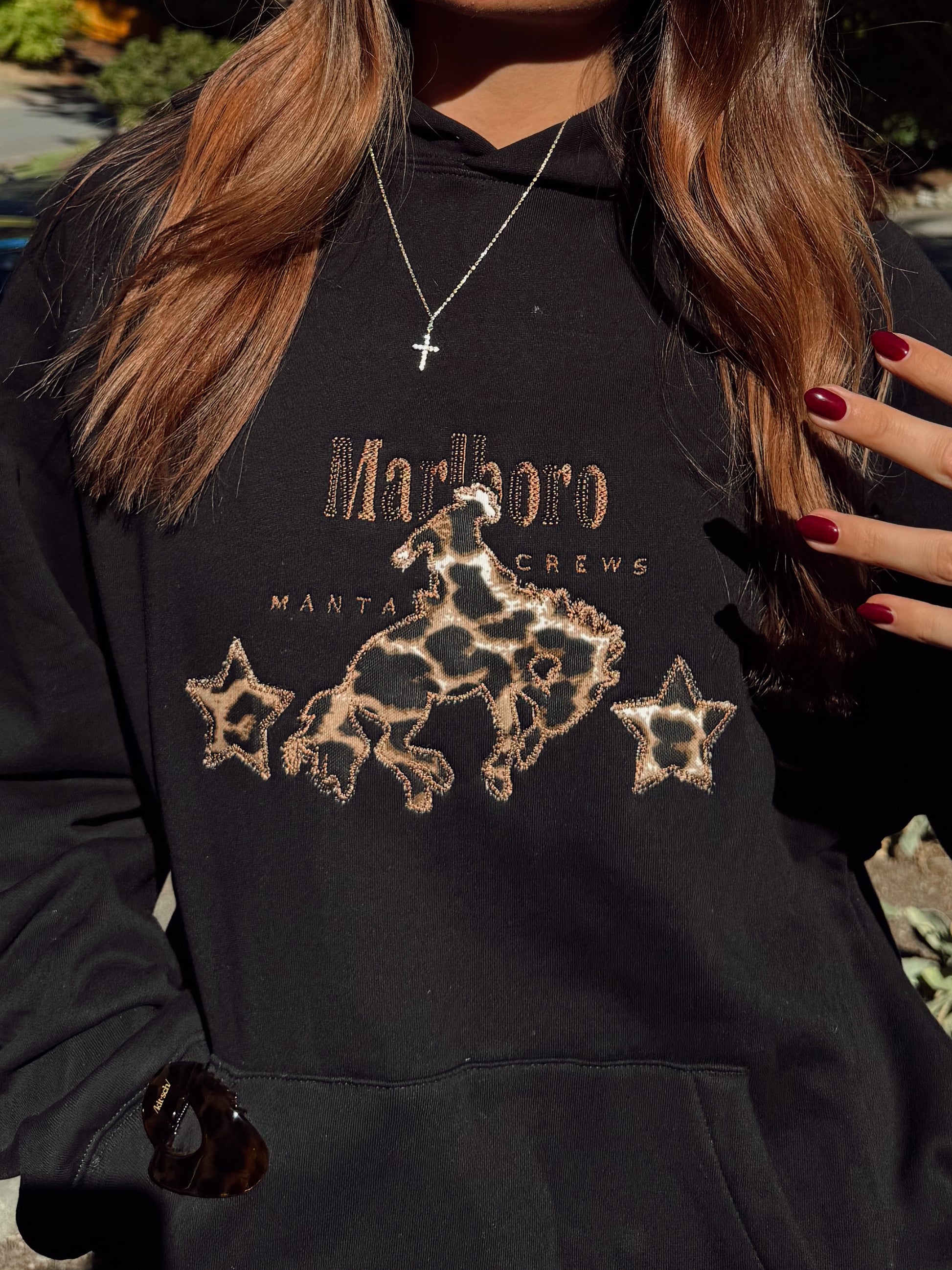 Girl wearing a black Marlboro western hoodie with a leopard print design embroidered onto it with brown thread