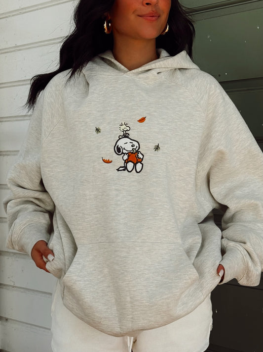 Girl wearing an oversized embroidered hoodie with a fall snoopy design in grey 